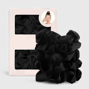Black satin scrunchies with packaging on a light gray background