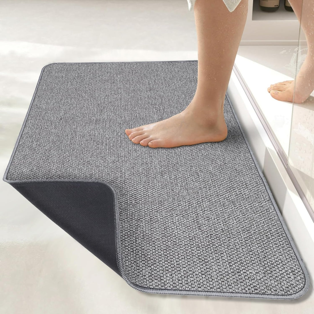 Person stepping onto a gray bath mat in a bathroom setting