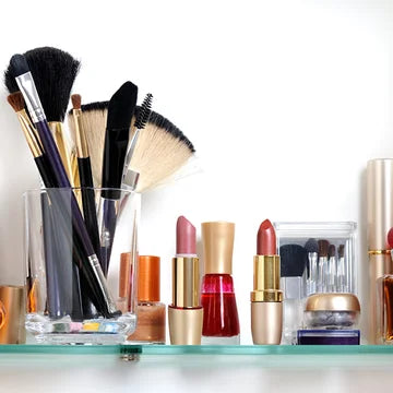 Makeup brushes and lipsticks on a glass shelf with a white background