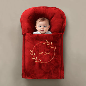 Baby wrapped in a red blanket with a logo on a beige background