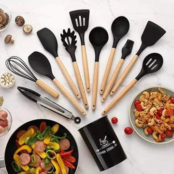 Set of black and wooden kitchen utensils on a white surface with food items.