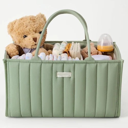 Green baby caddy with a teddy bear, diapers, and other items on a white background
