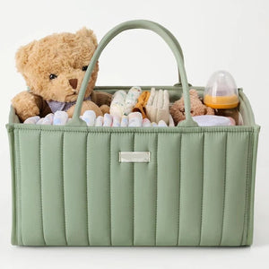 Green baby caddy with a teddy bear, diapers, and other items on a white background